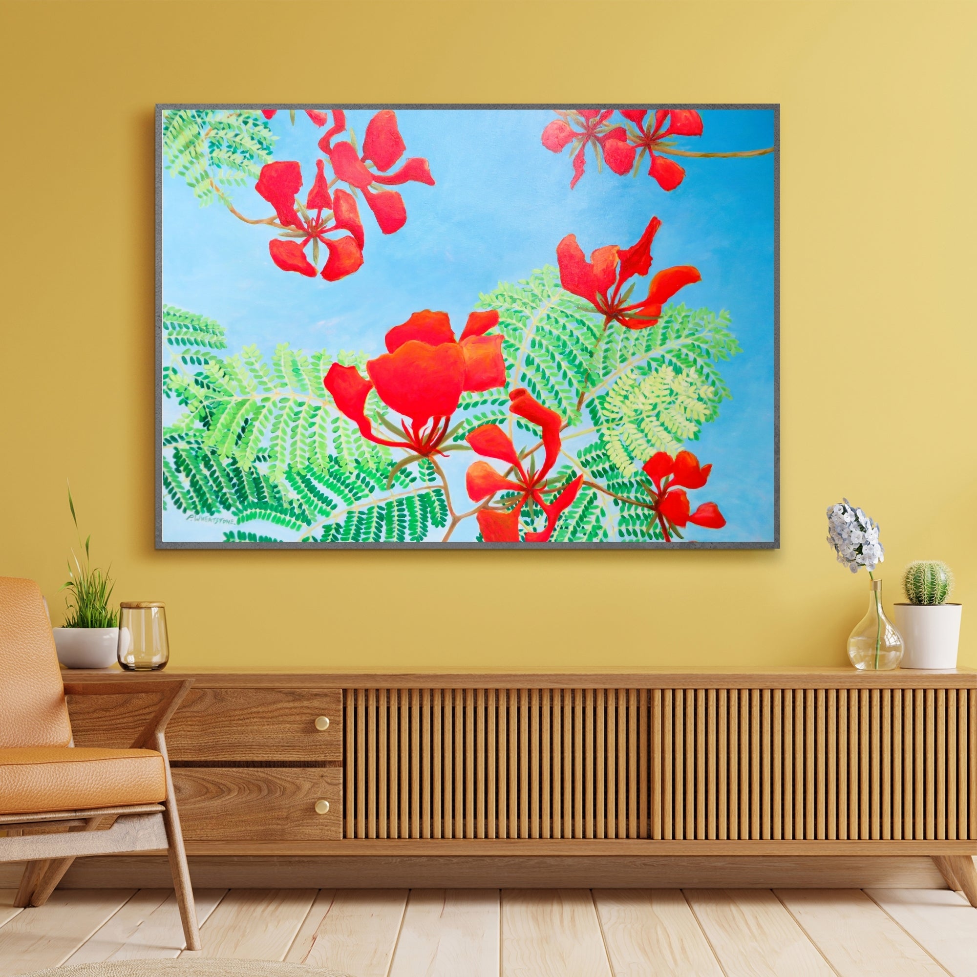 Image of an acrylic painting depicting bright red poinciana flowers and leaves against a clear blue sky, in a living room setting with a mustard yellow wall